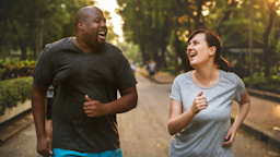 Two friends on a run together. They are looking at each other and laughing.
Rawpixel/iStock via Getty Images