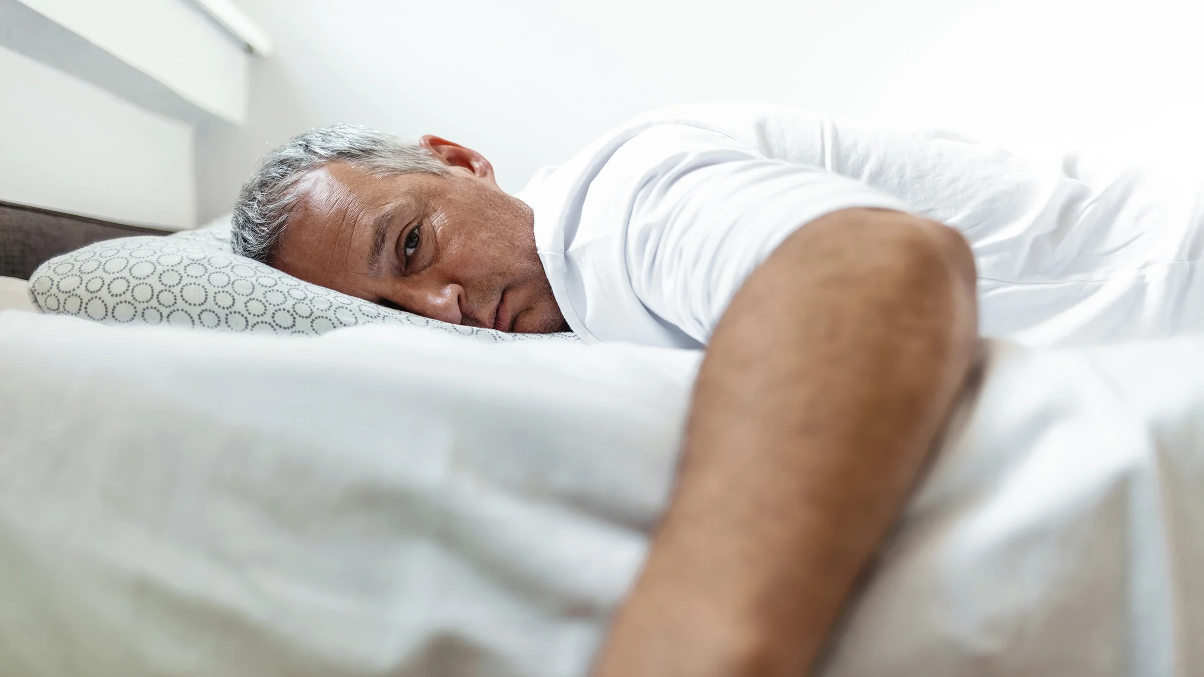 A man looks anxious with insomnia in bed.
