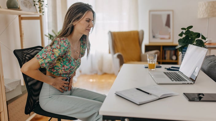 A person experiencing stomach cramps at their desk.
