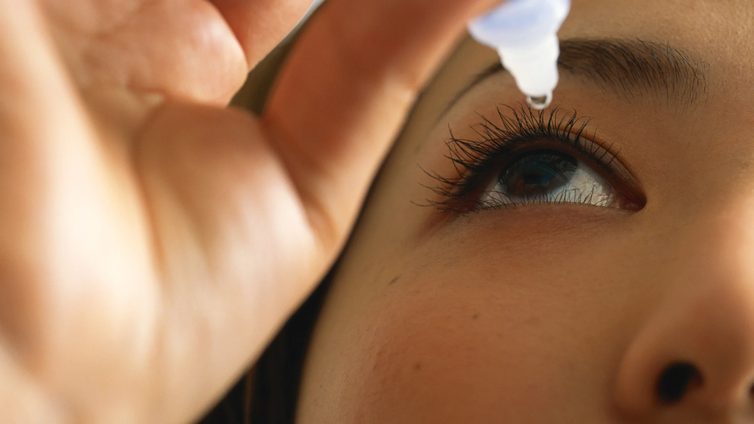 Close-up of someone using eye drops.