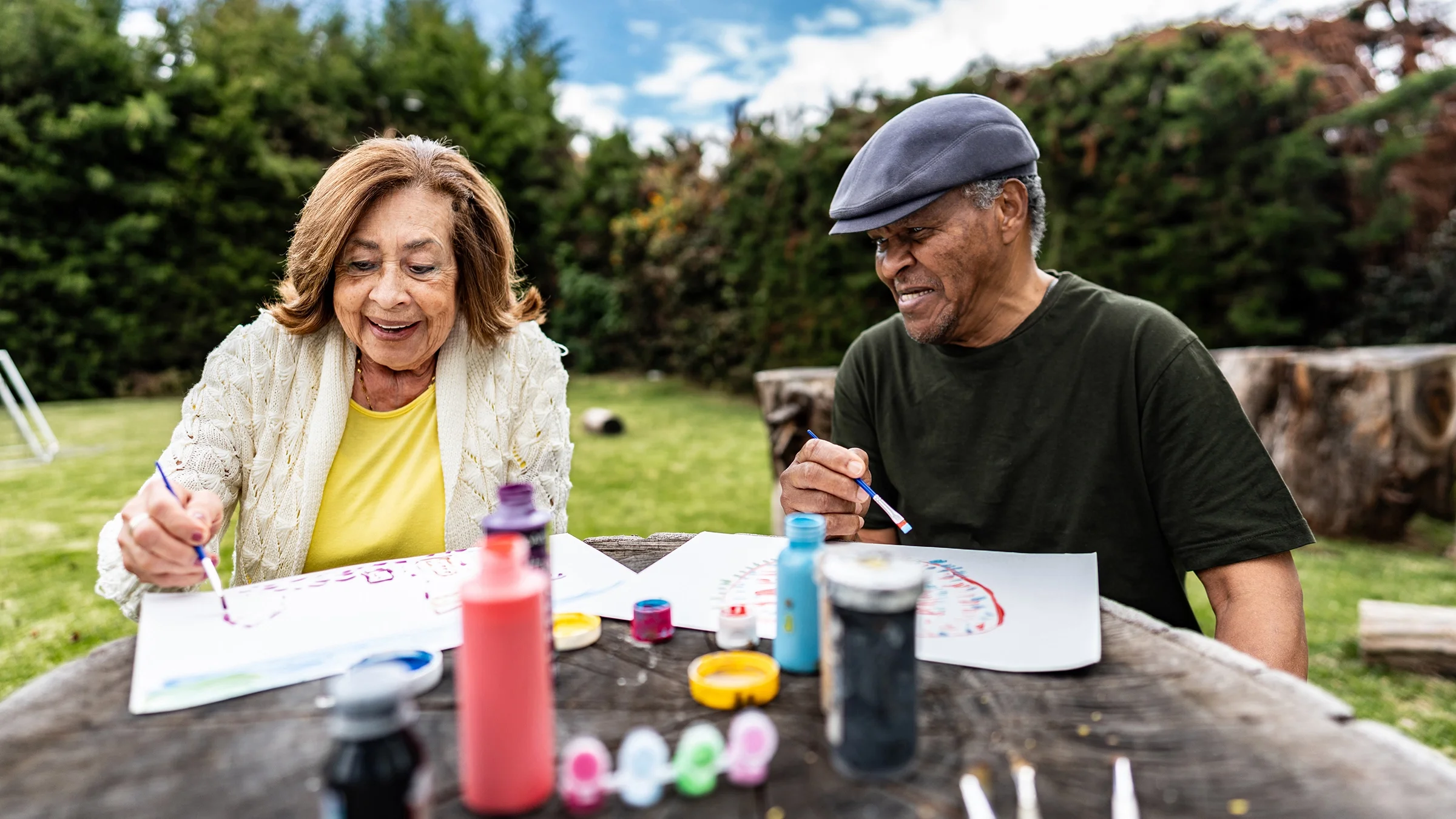A woman and a man enjoy painting outdoors.