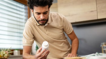 Pharmacy: man reading medication bottle 1457121408