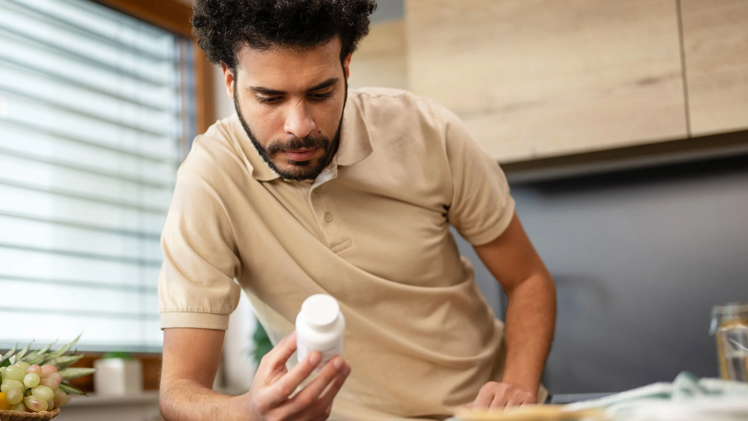 A man reads the side of a prescription bottle.