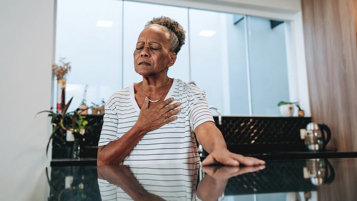 A woman places her hand on her chest as she experiences chest pain. 