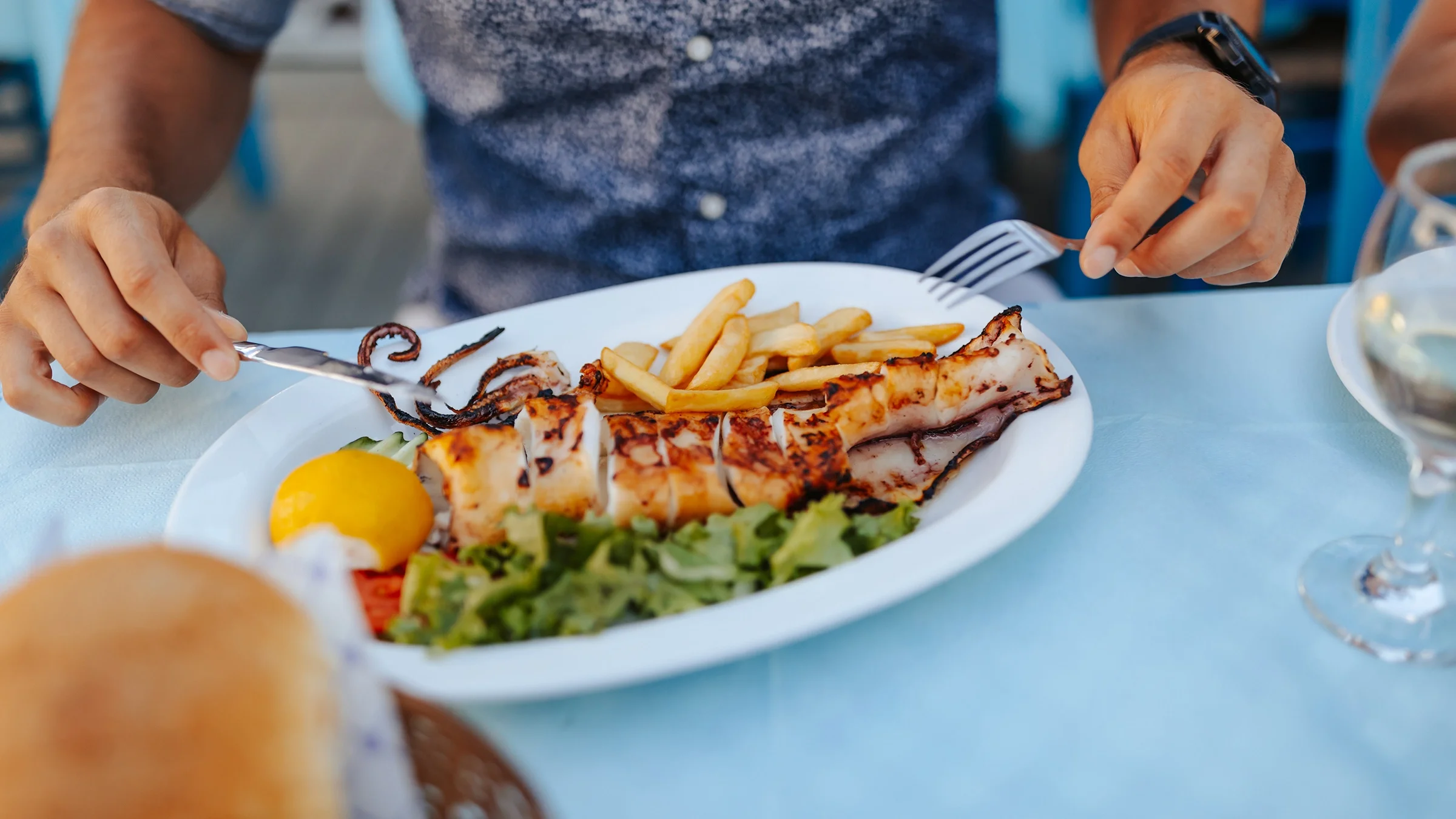 Cropped shot of a person enjoying a healthy Mediterranean lunch outdoors. It looks like some sort of fish on his plate with a side salad.