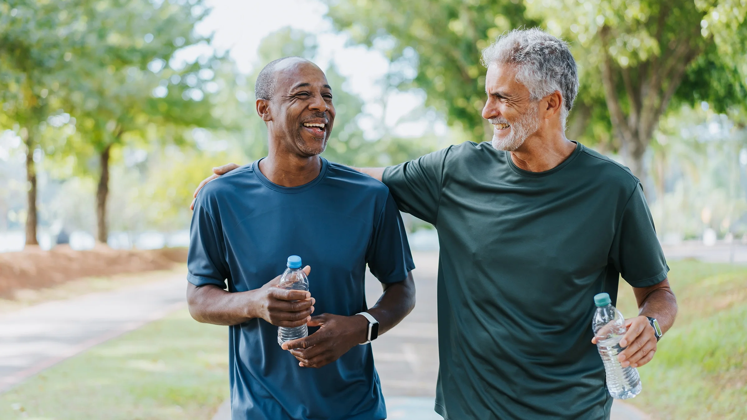 Two men smile while walking in a park. 