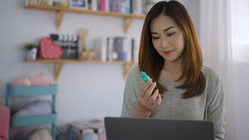 Drug cost and savings: holding eye drop researching on laptop 1423344553