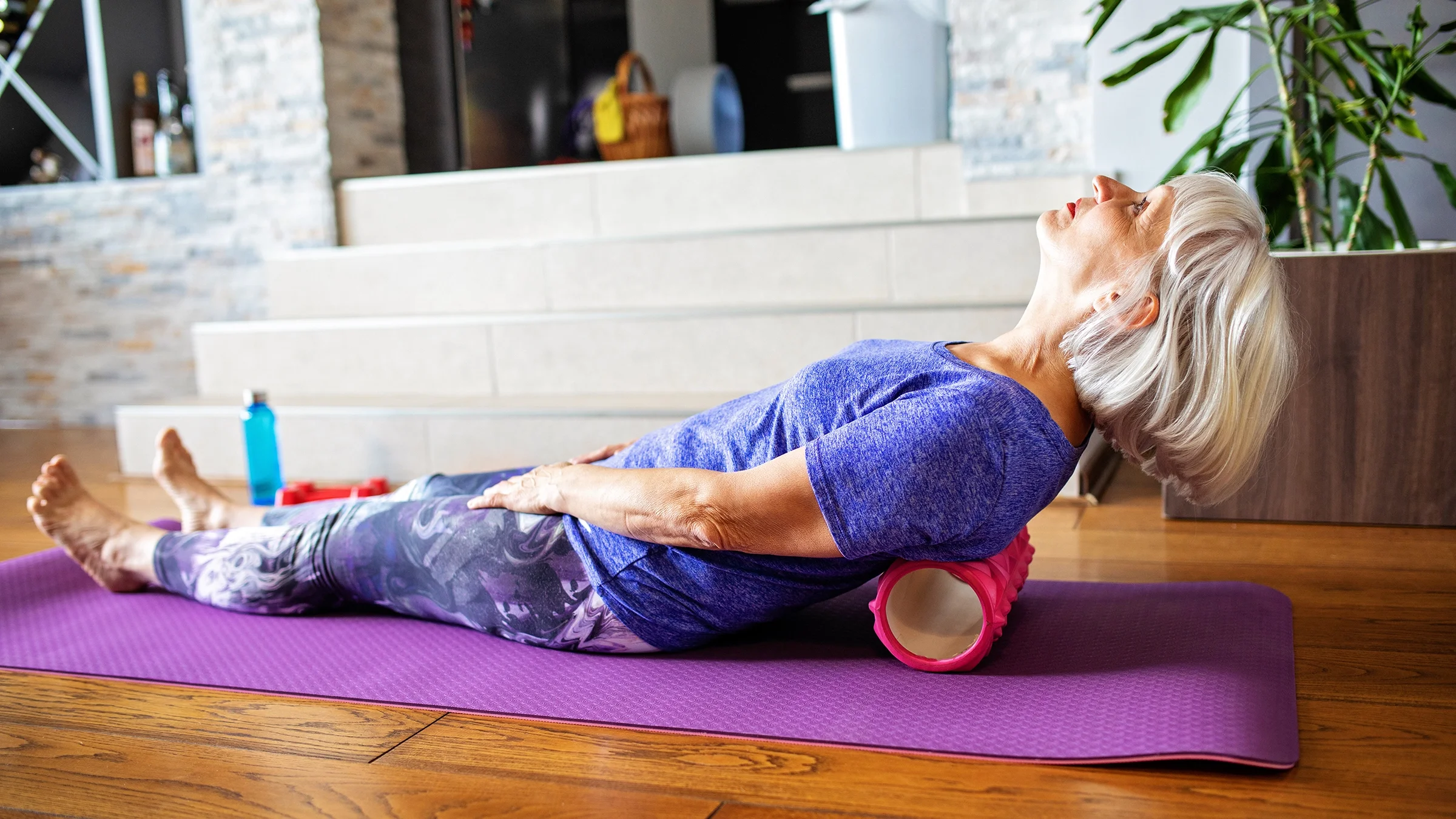 Older woman rolling on foam roller after an at home workout.