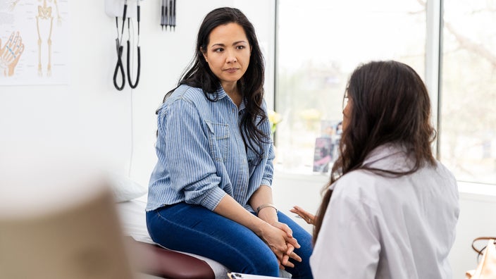 A woman listens to a healthcare provider during a medical appointment.