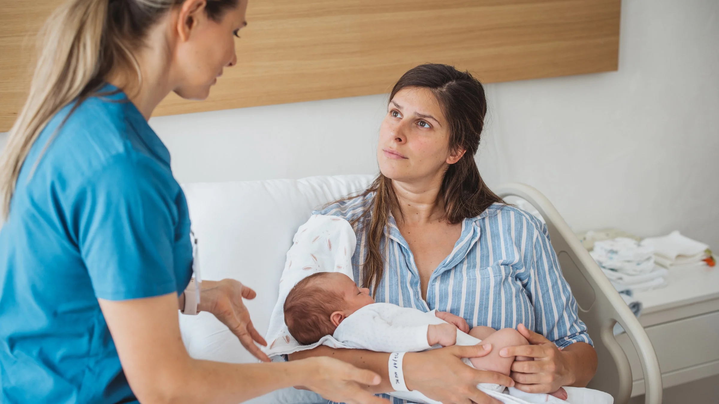 A parent holding a newborn and talking to a doctor.