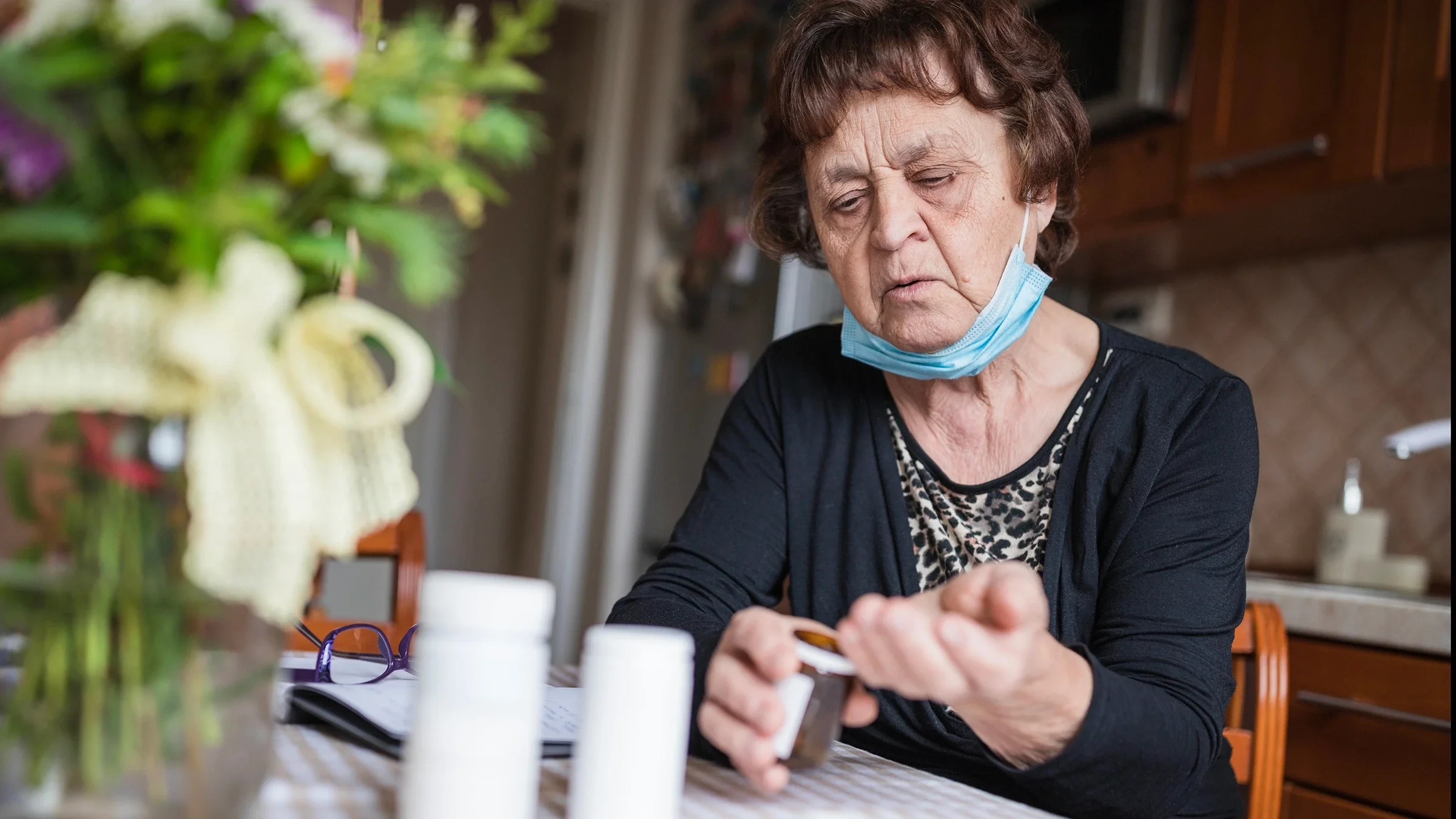 Senior woman taking her pills at her dining table.