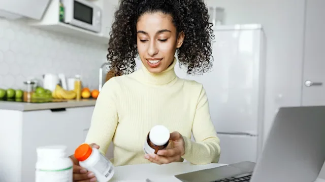 Supplements-herbs: woman reading supplement bottles 2218539362