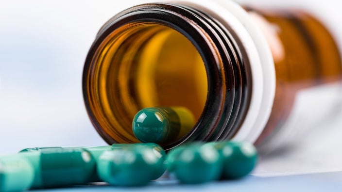 Green capsule spilling out of a bottle.