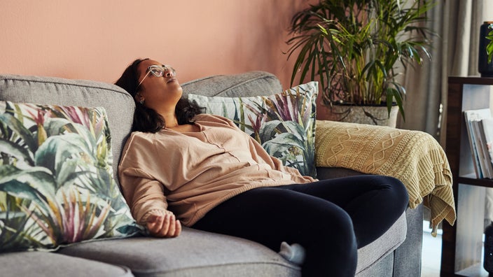 A woman is slumped on the sofa at home.