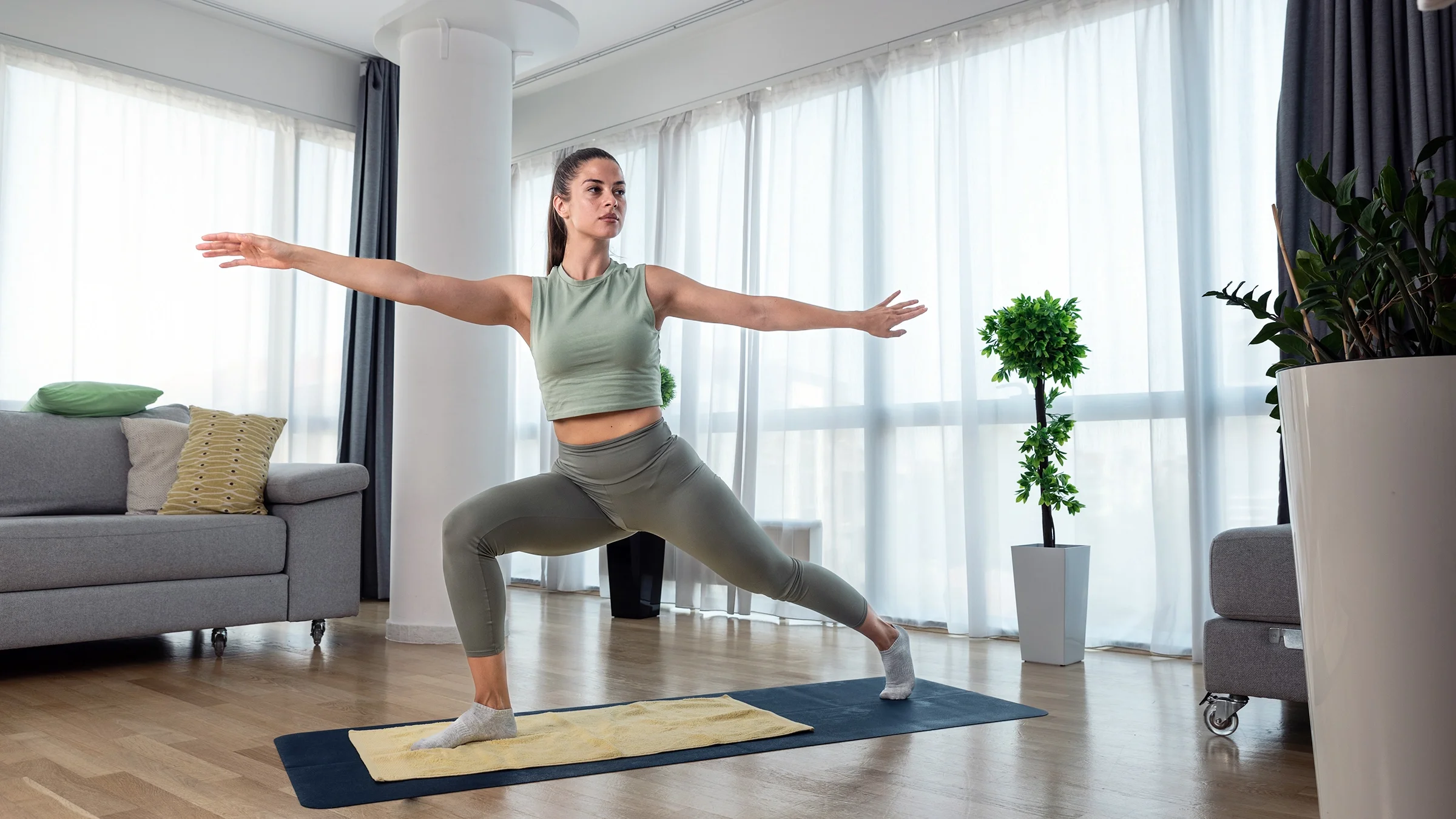 A woman practices a yoga routine at home.