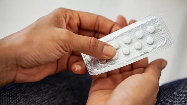 Clomid: closeup hands retrieving pills from a blister pack 1490530108