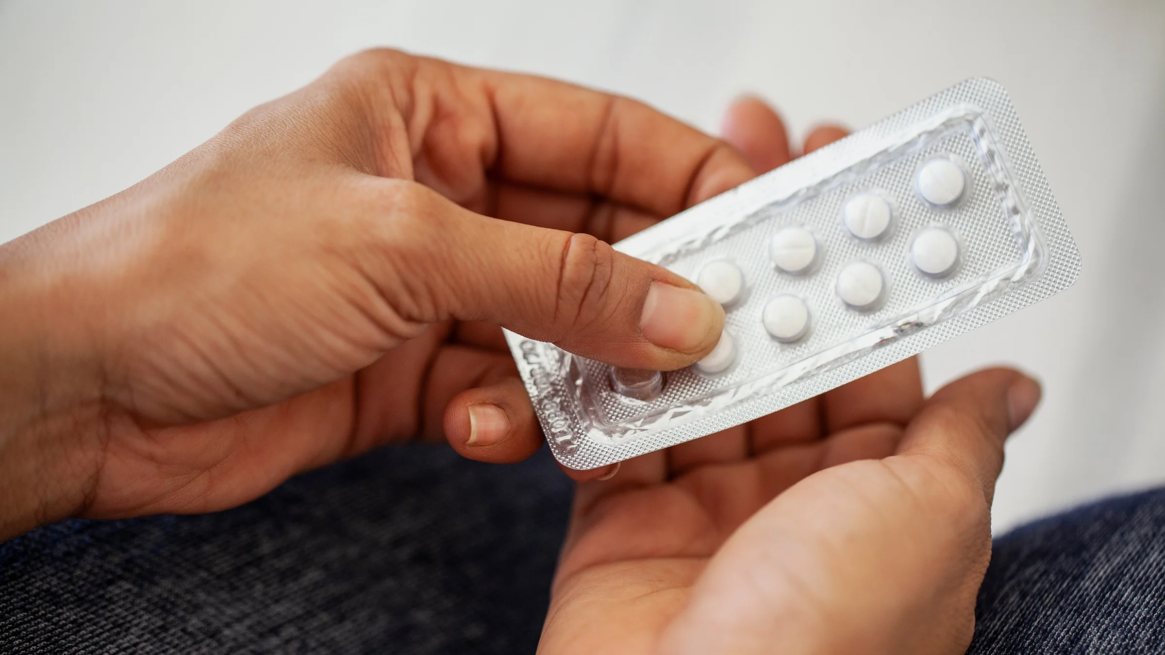 A person retrieves medication from a blister pack.
