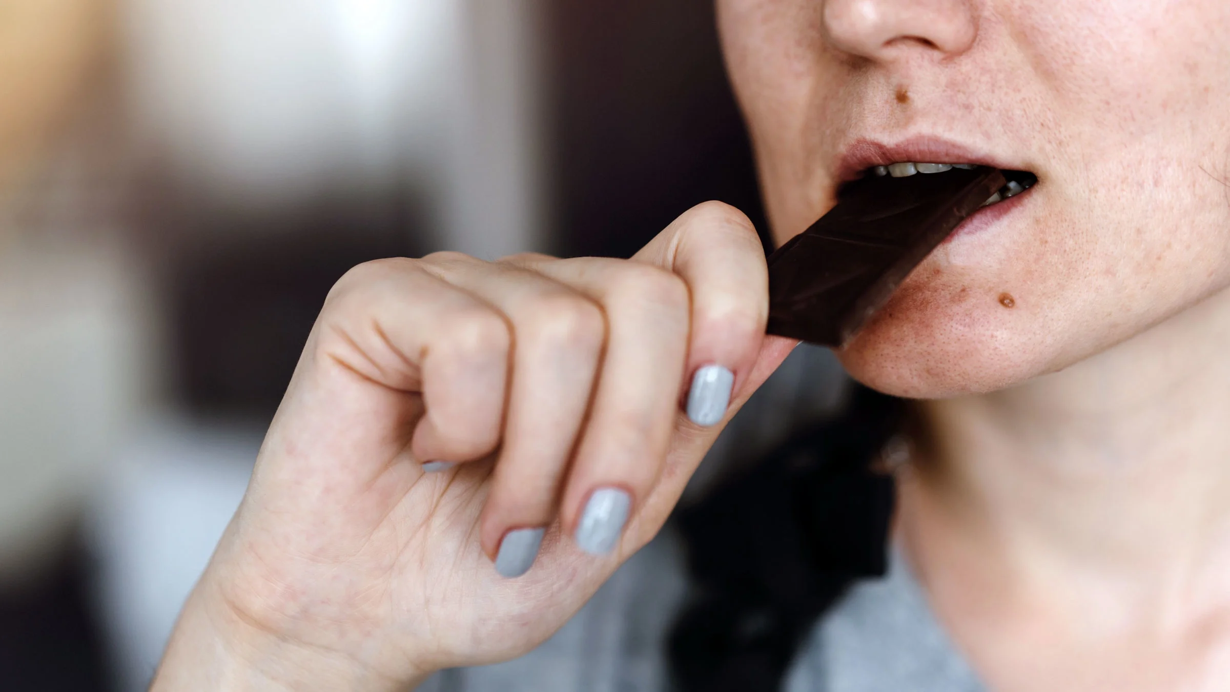 A woman is eating dark chocolate.