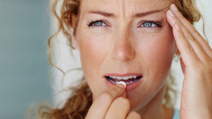 A person taking a pill for a headache.