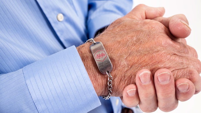Close-up of older man wearing a medical alert bracelet.