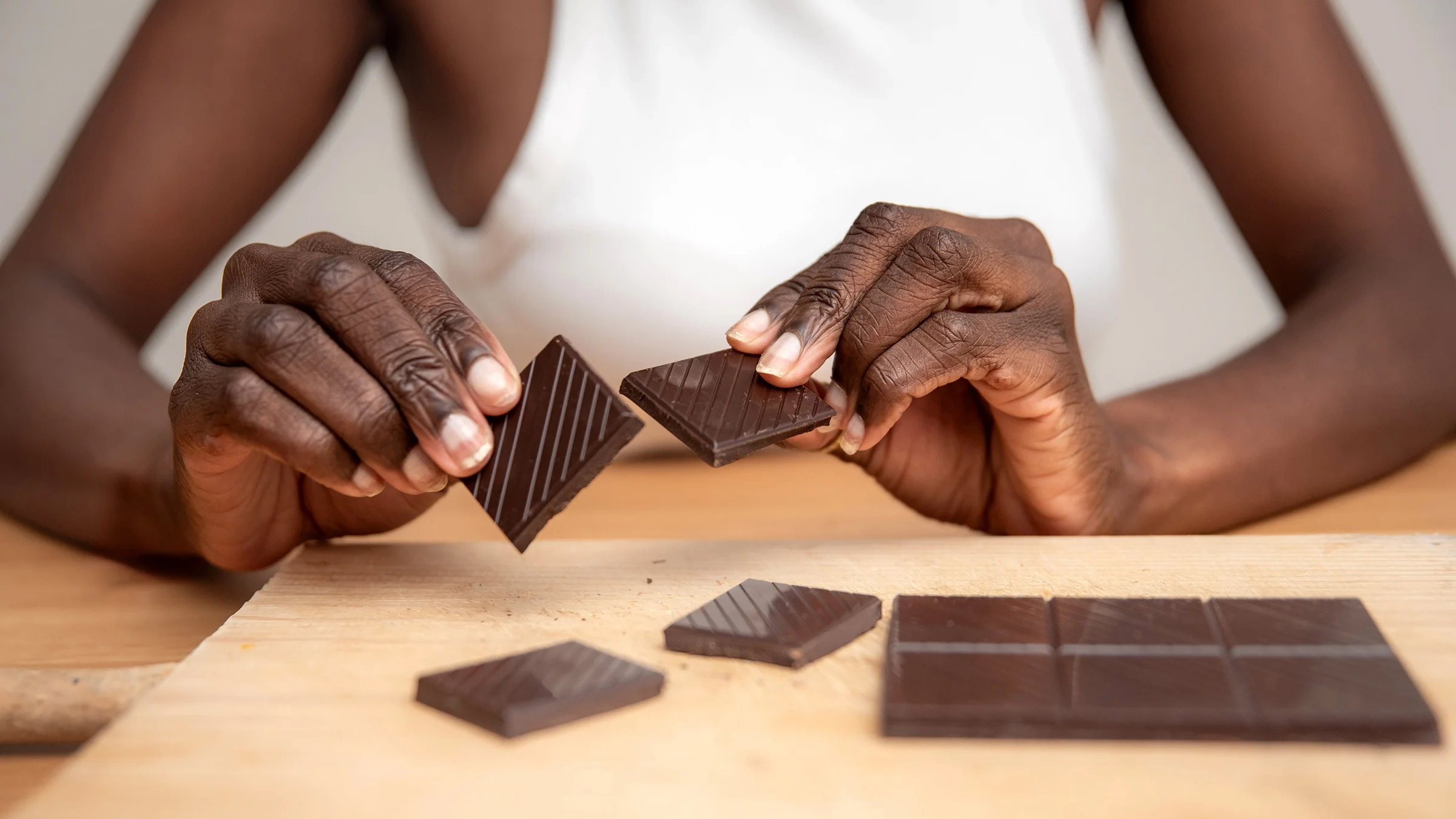 A woman breaks a dark chocolate bar.