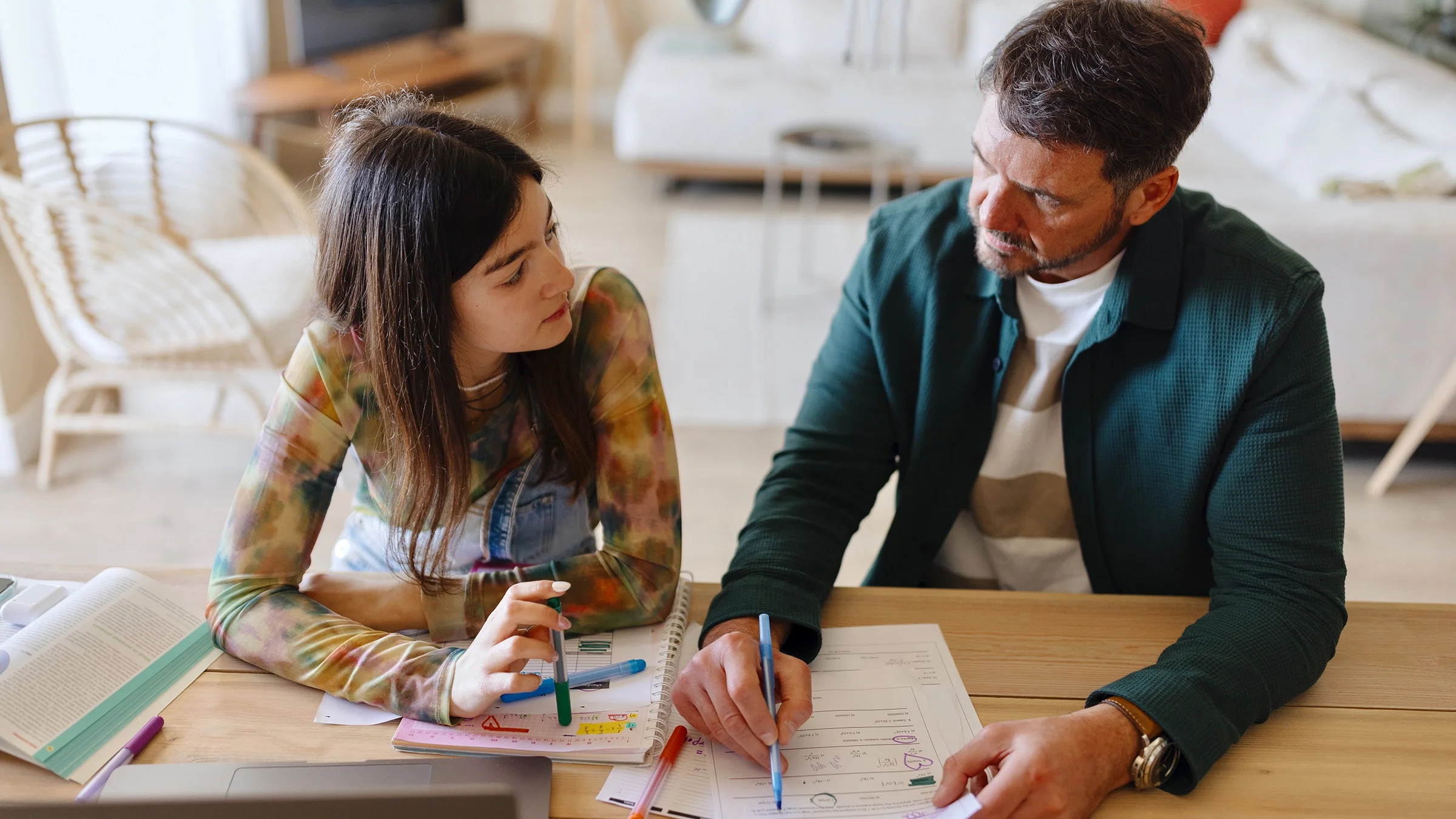 A father is helping his teenage daughter with homework.