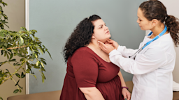 Woman on the exam table having the doctor do a thyroid check.
peakSTOCK/iStock via Getty Images
