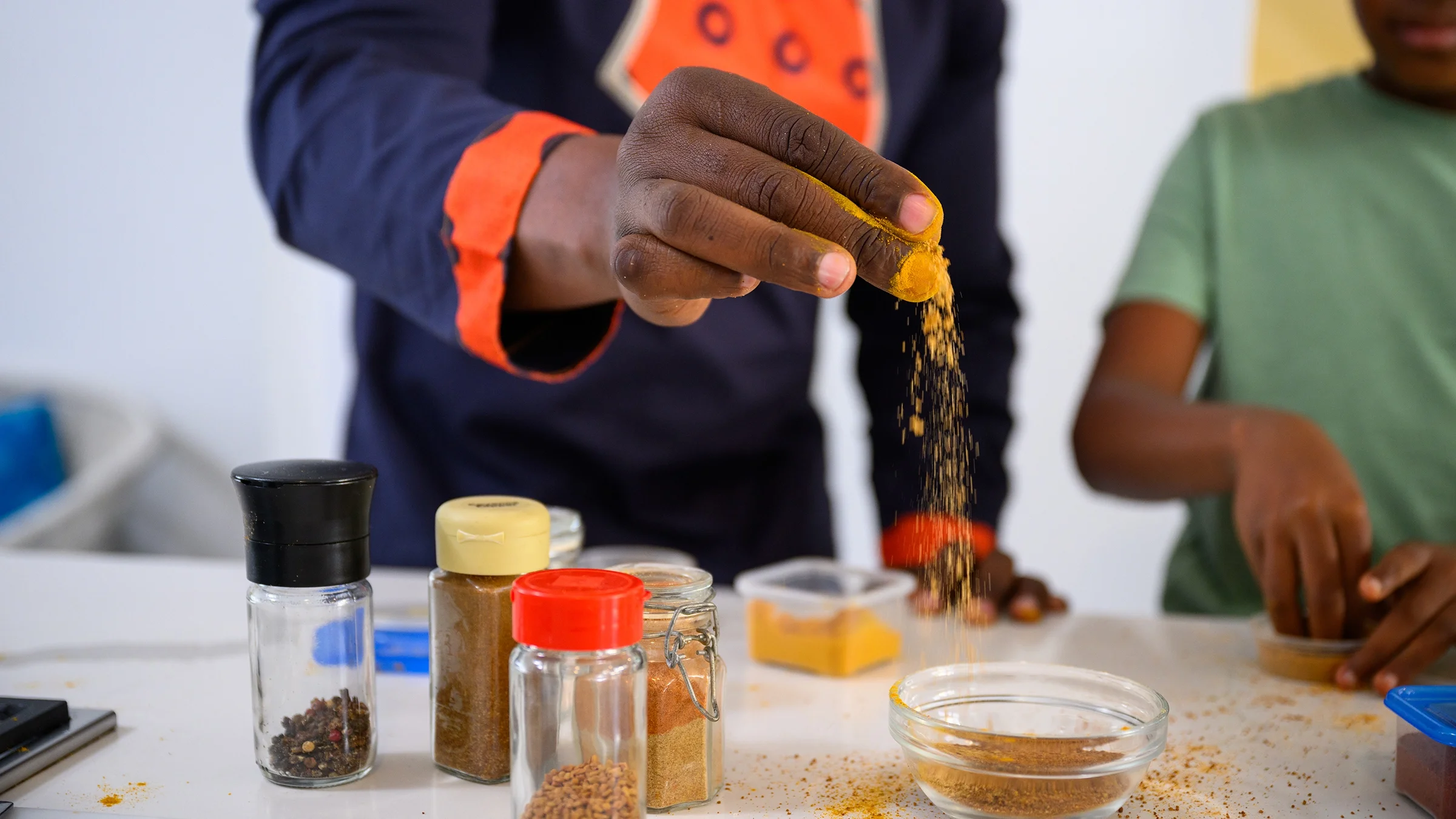 Close-up hand adding spice while cooking.