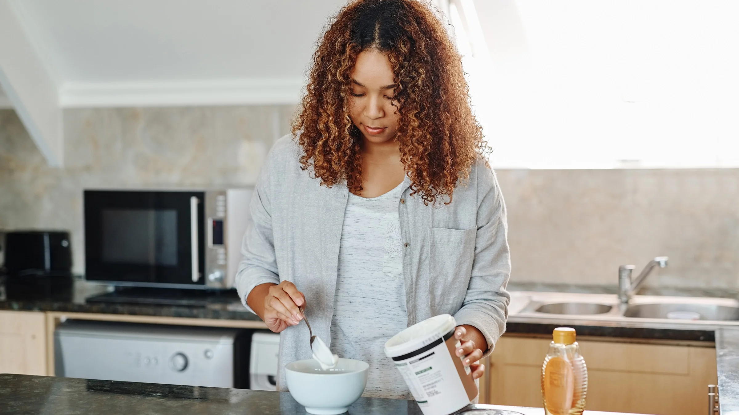 A woman spoons yogurt into a bowl.
