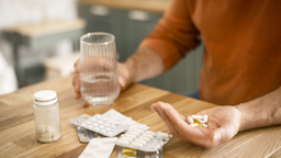 Close-up man taking medicine in kitchen.
elenaleonova/E+ via Getty Images