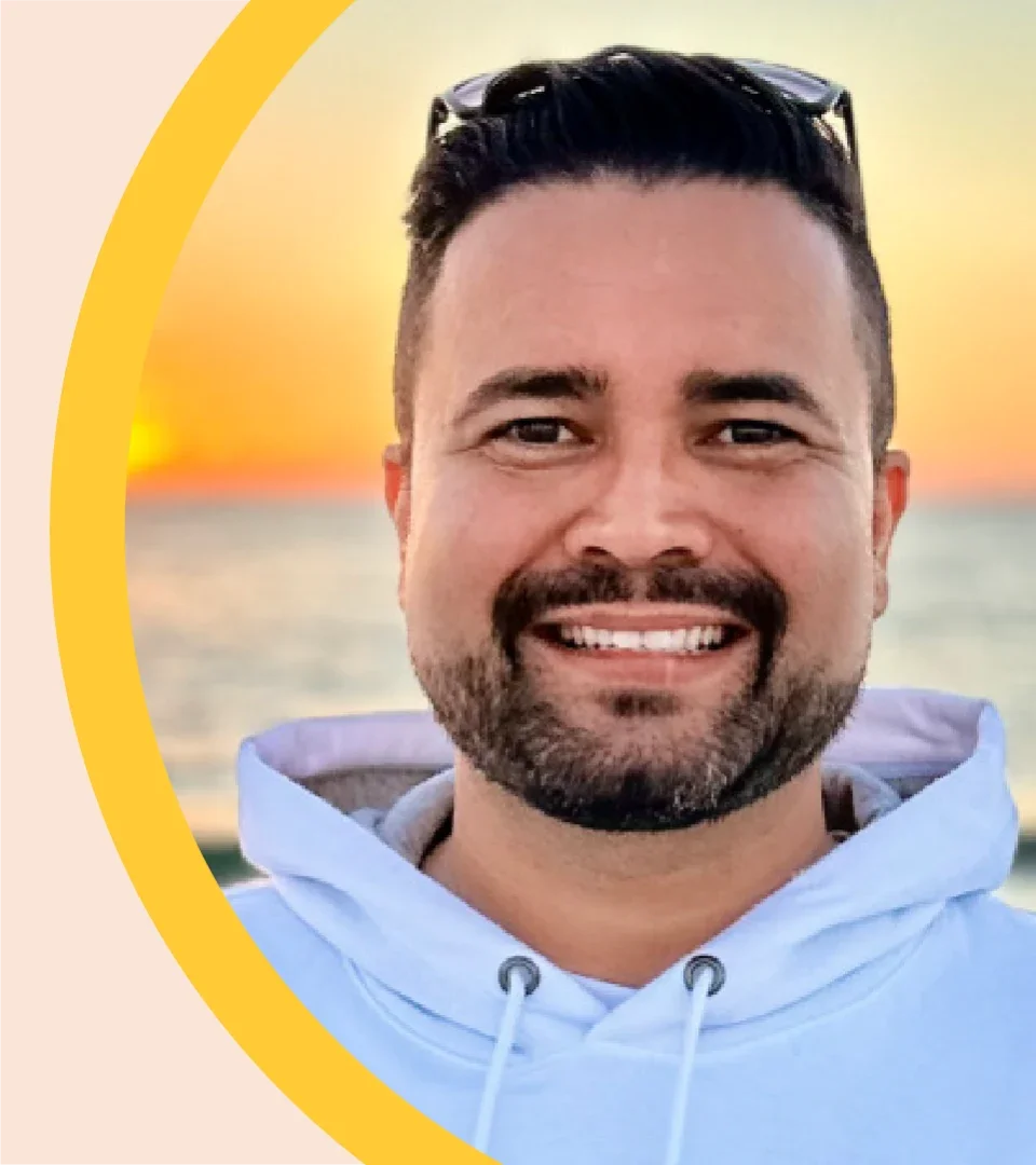 Ricardo Louzada is pictured outdoors, with the sun setting behind him.