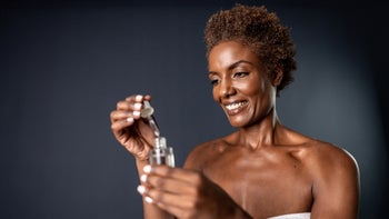 Dermatology: woman using facial serum 2156053575