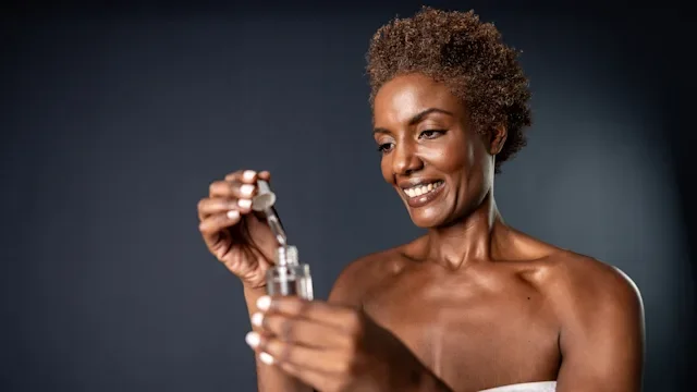 Dermatology: woman using facial serum 2156053575