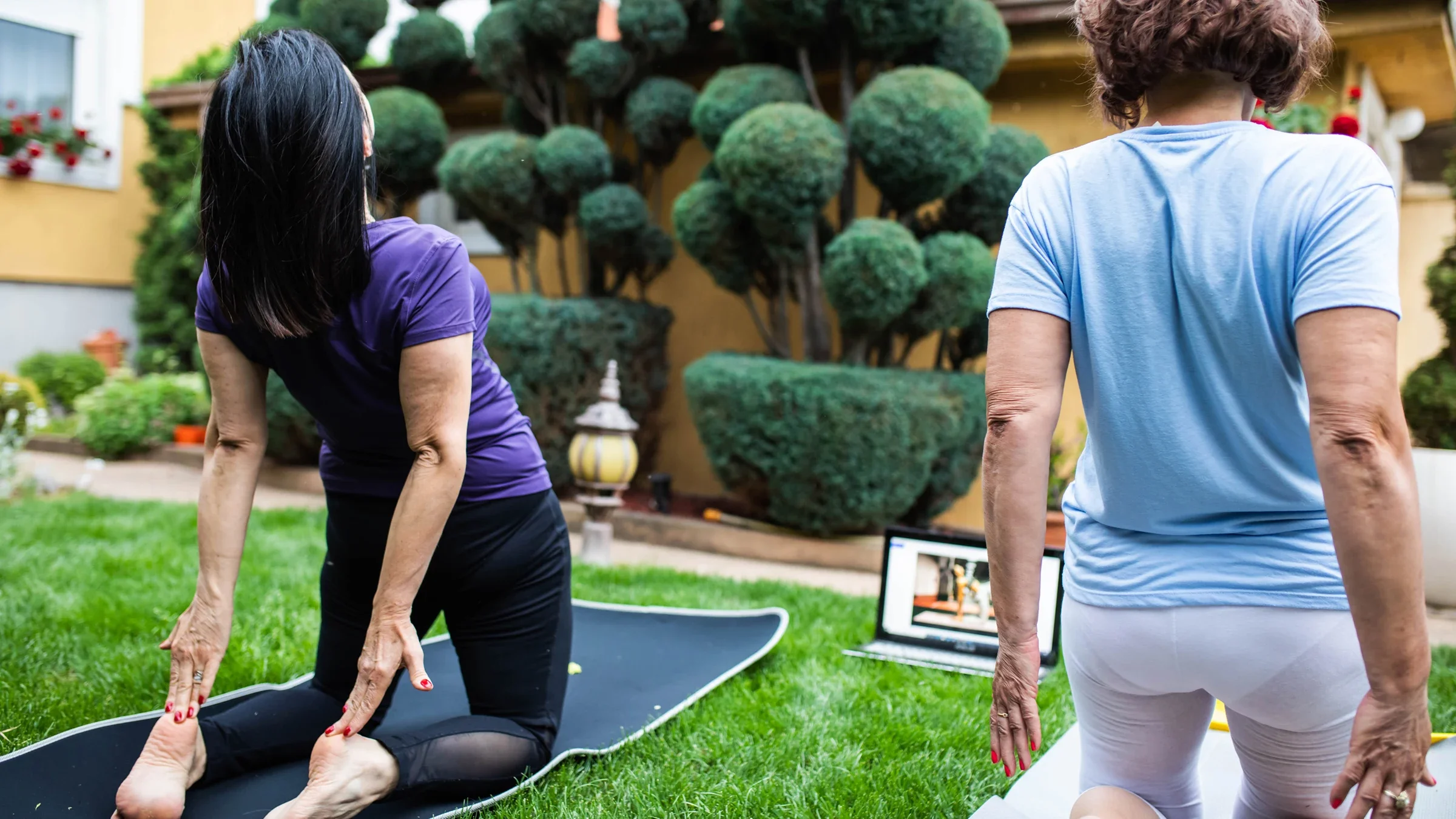 Women do a yoga exercise outdoors with a video on a laptop.
Aleksandar Jankovic/E+ via Getty Images