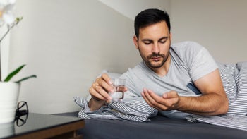 trazodone: pills: man laying in bed taking pills 996171856