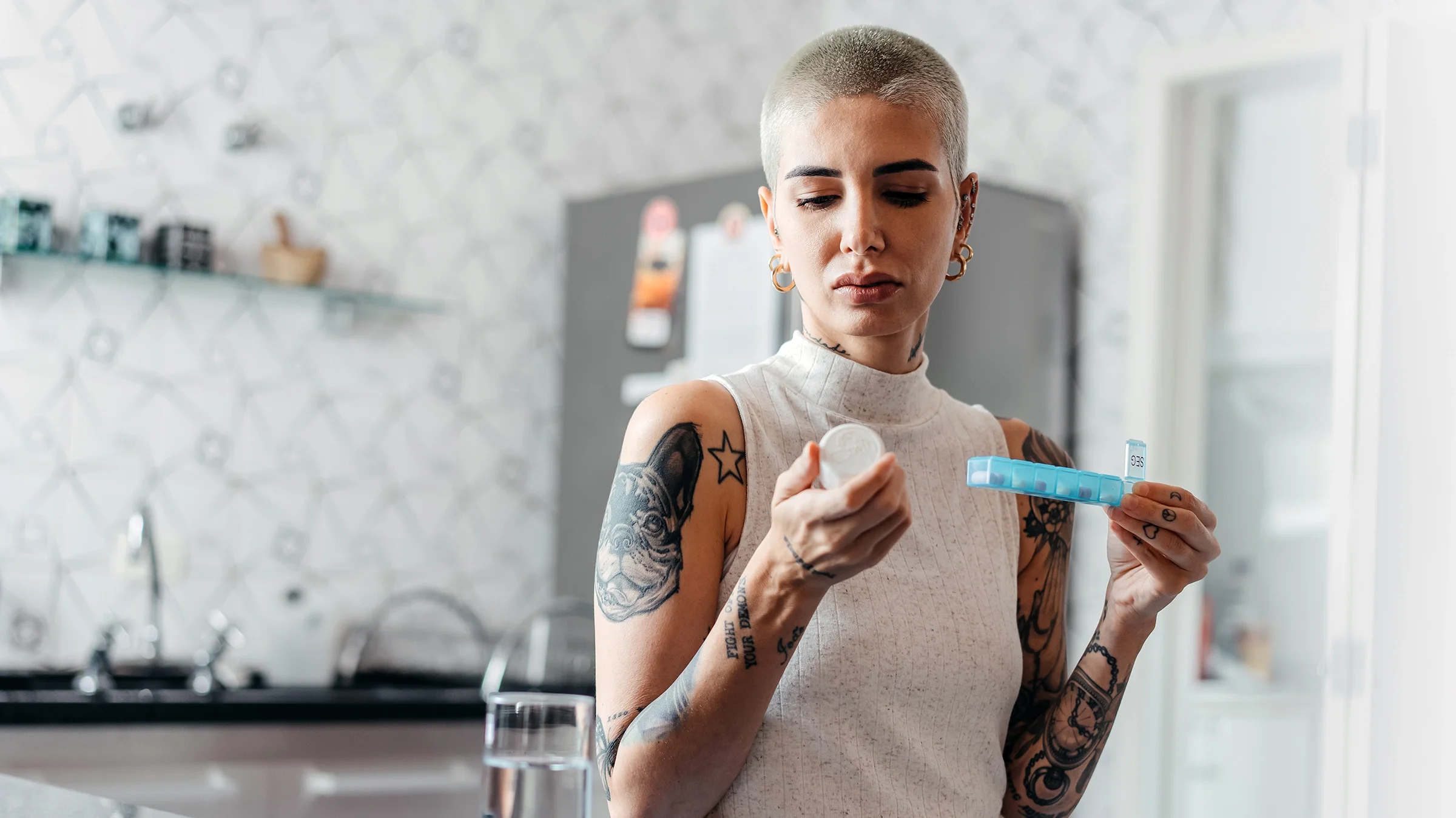 A woman studies her medication in her kitchen.