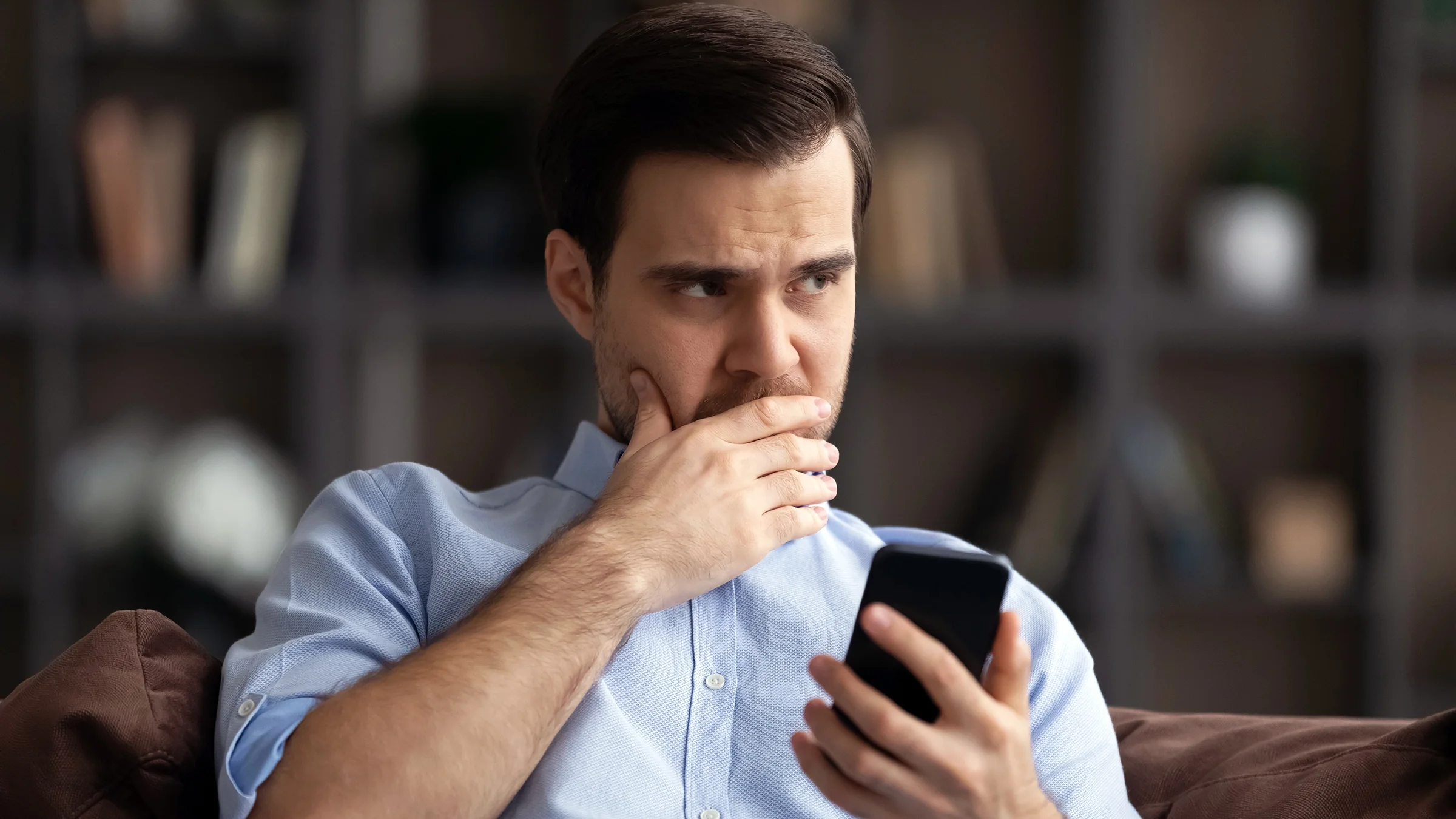 A man holds a phone and hesitates before making a call.