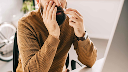 A man sitting at an office desk uses a nasal spray.
LightFieldStudios/iStock via Getty Images Plus