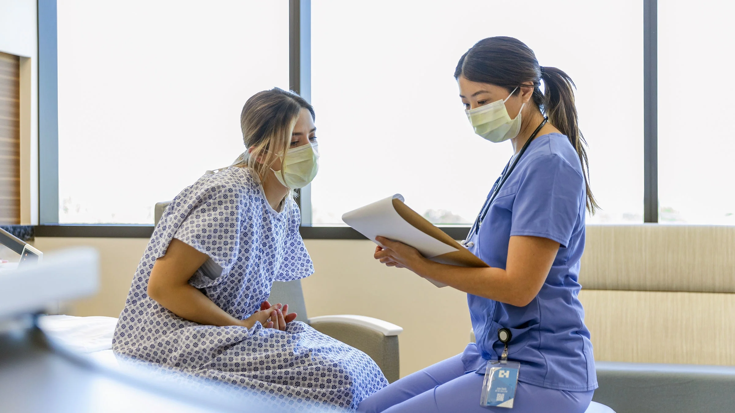 An adult is sitting on a hospital bed and looking at test results.