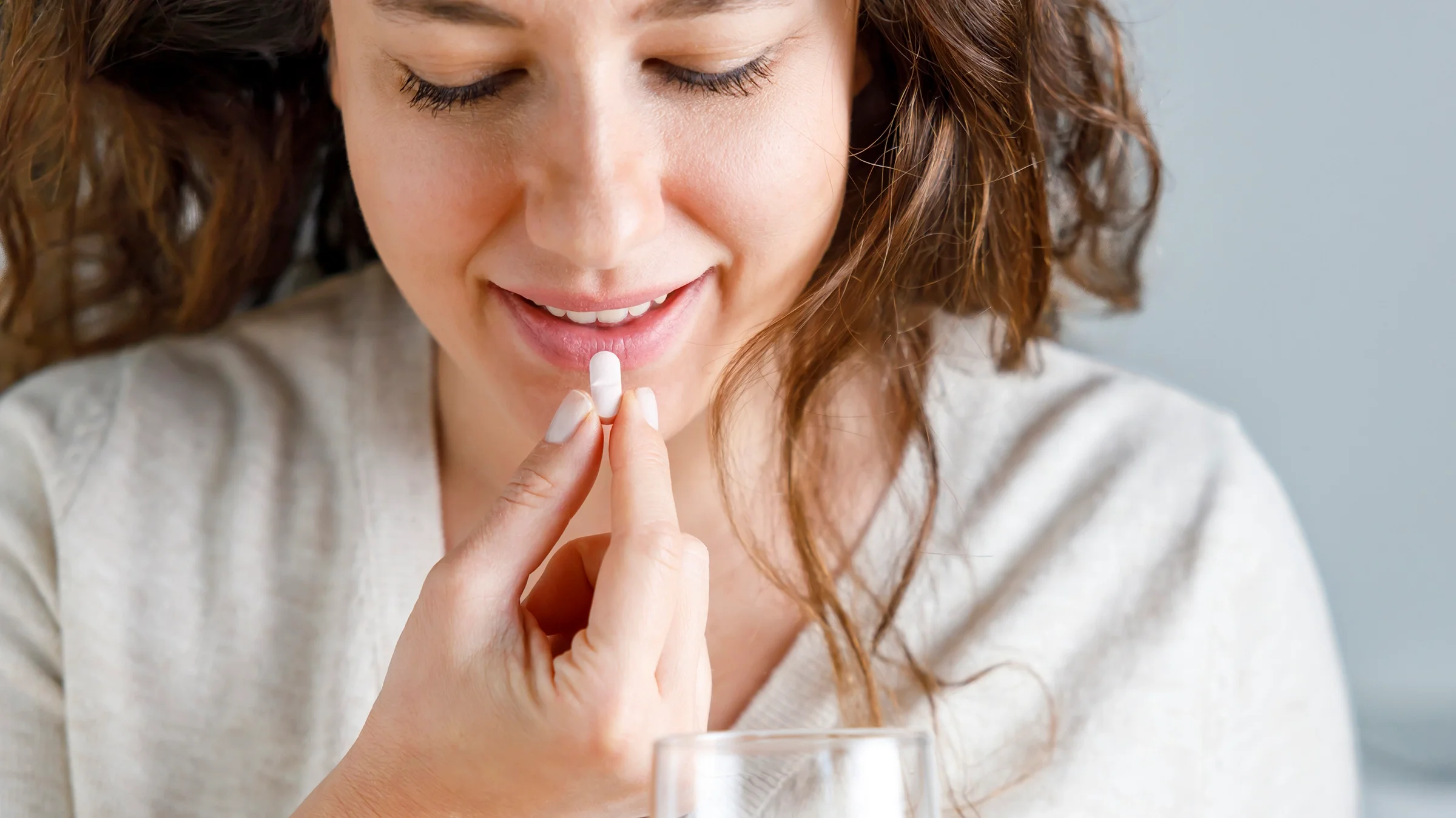 Cropped shot of a young woman taking one white pill.
