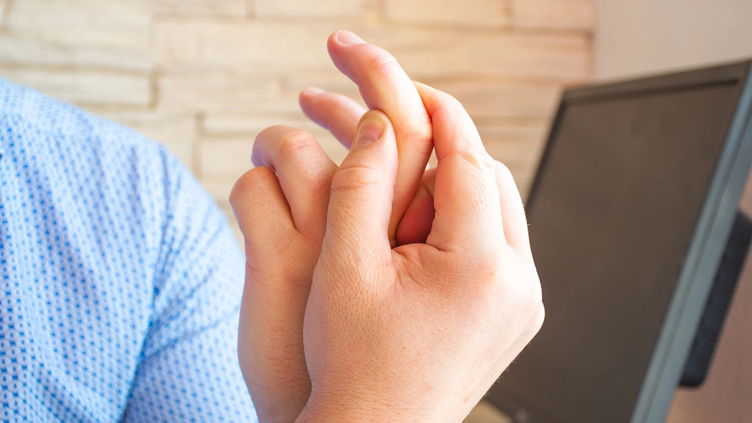 Close-up of a person' holding their pointer finger showing the knuckle that is in pain.