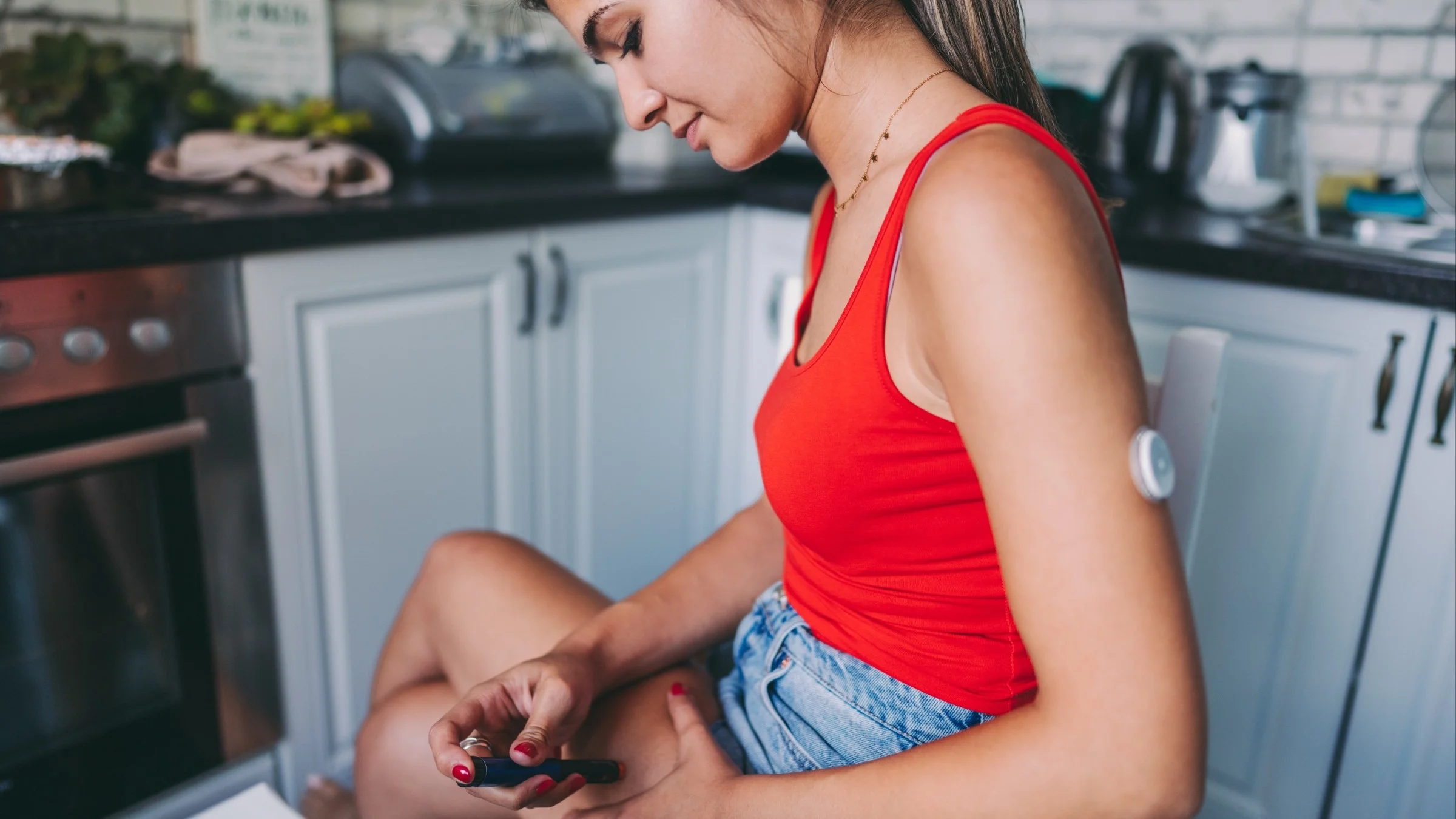 Young woman sitting with her legs crossed using an insulin injector on her thigh.