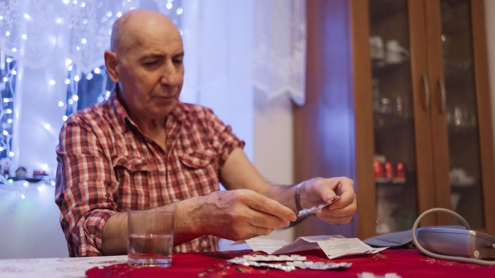An older man looks over his medications.