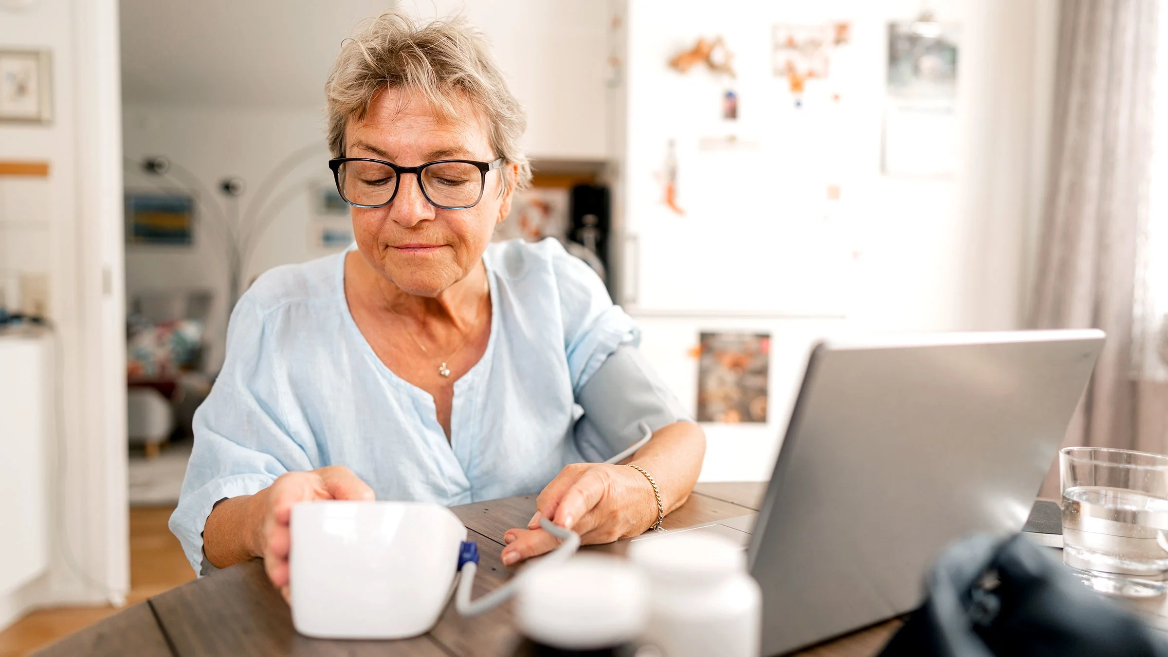 A senior woman waits for results after checking her blood pressure at home.