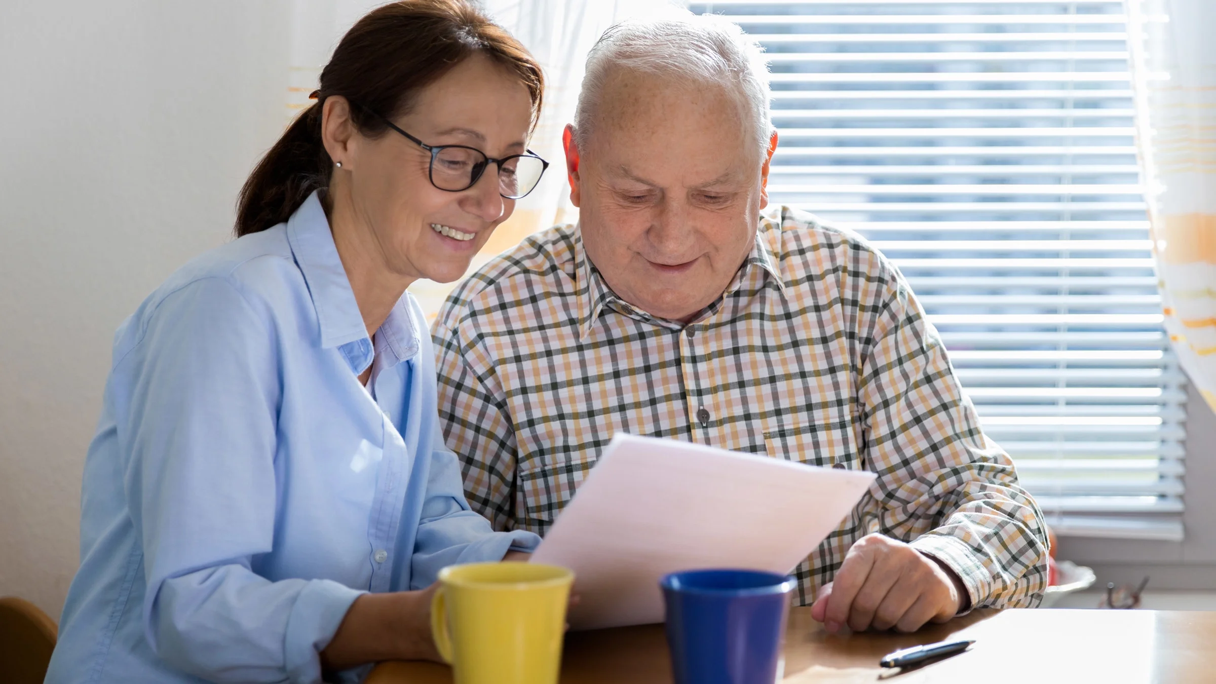 A caregiver helping an older man read paperwork.
