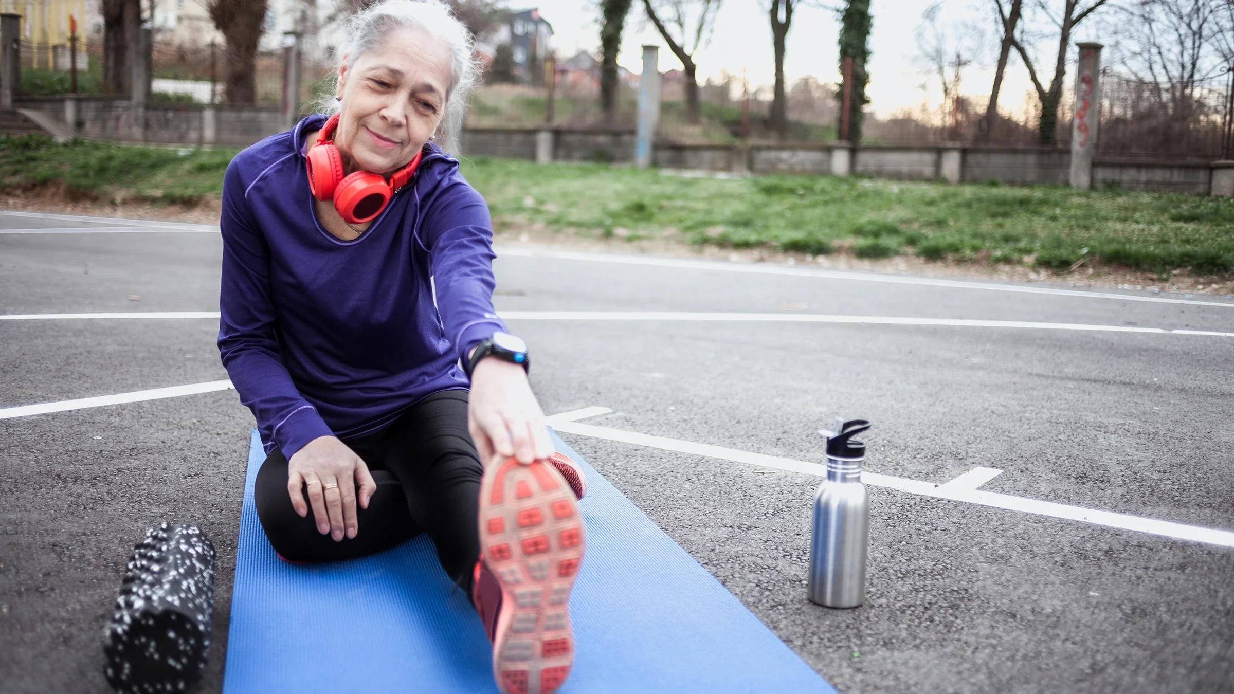 A woman stretches after working out. To prevent leg cramps, you can try some electrolyte-rich drinks.