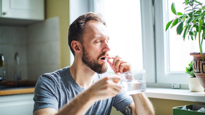 A man is taking medication at home.