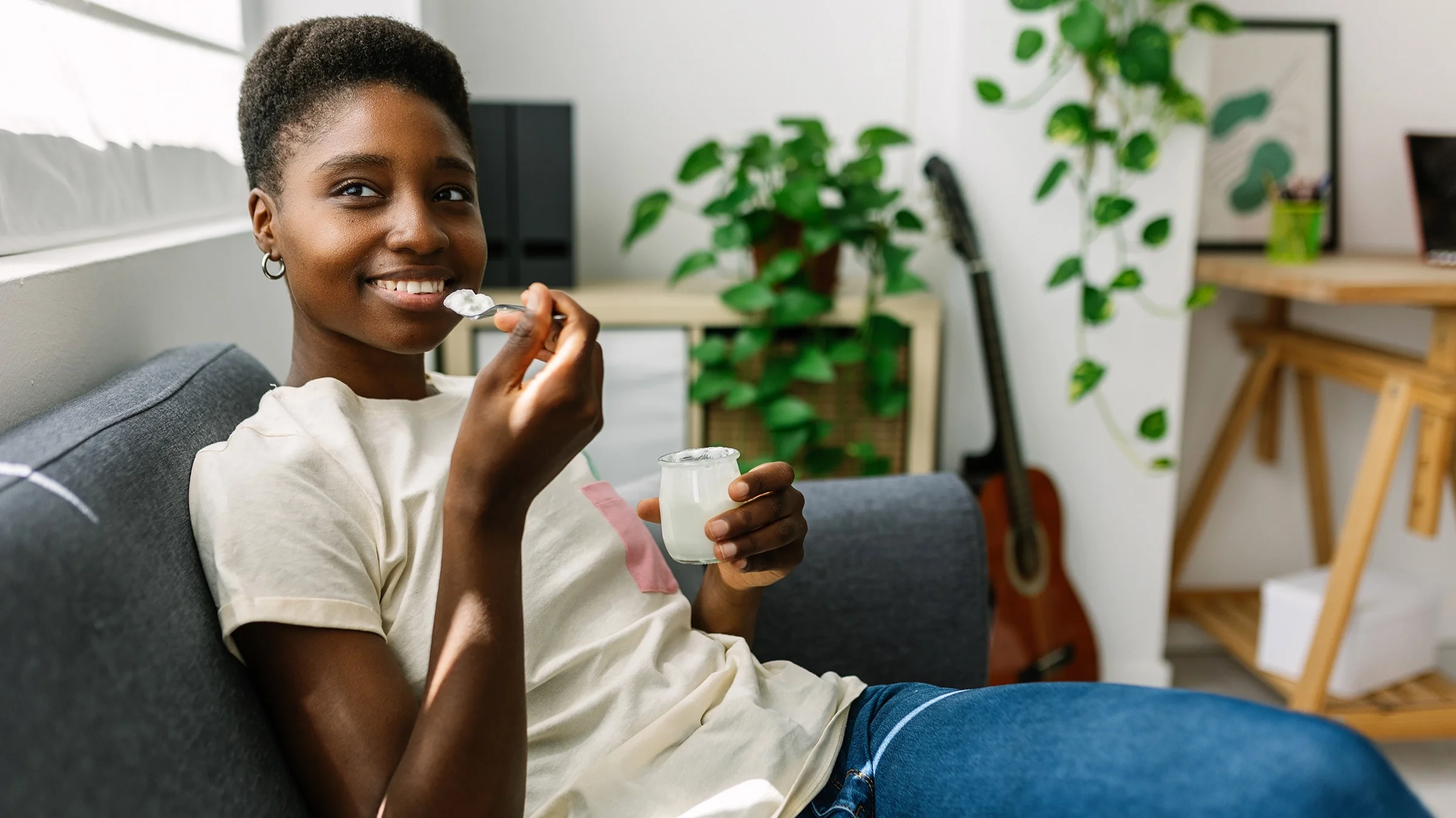 A woman eats yogurt at home.