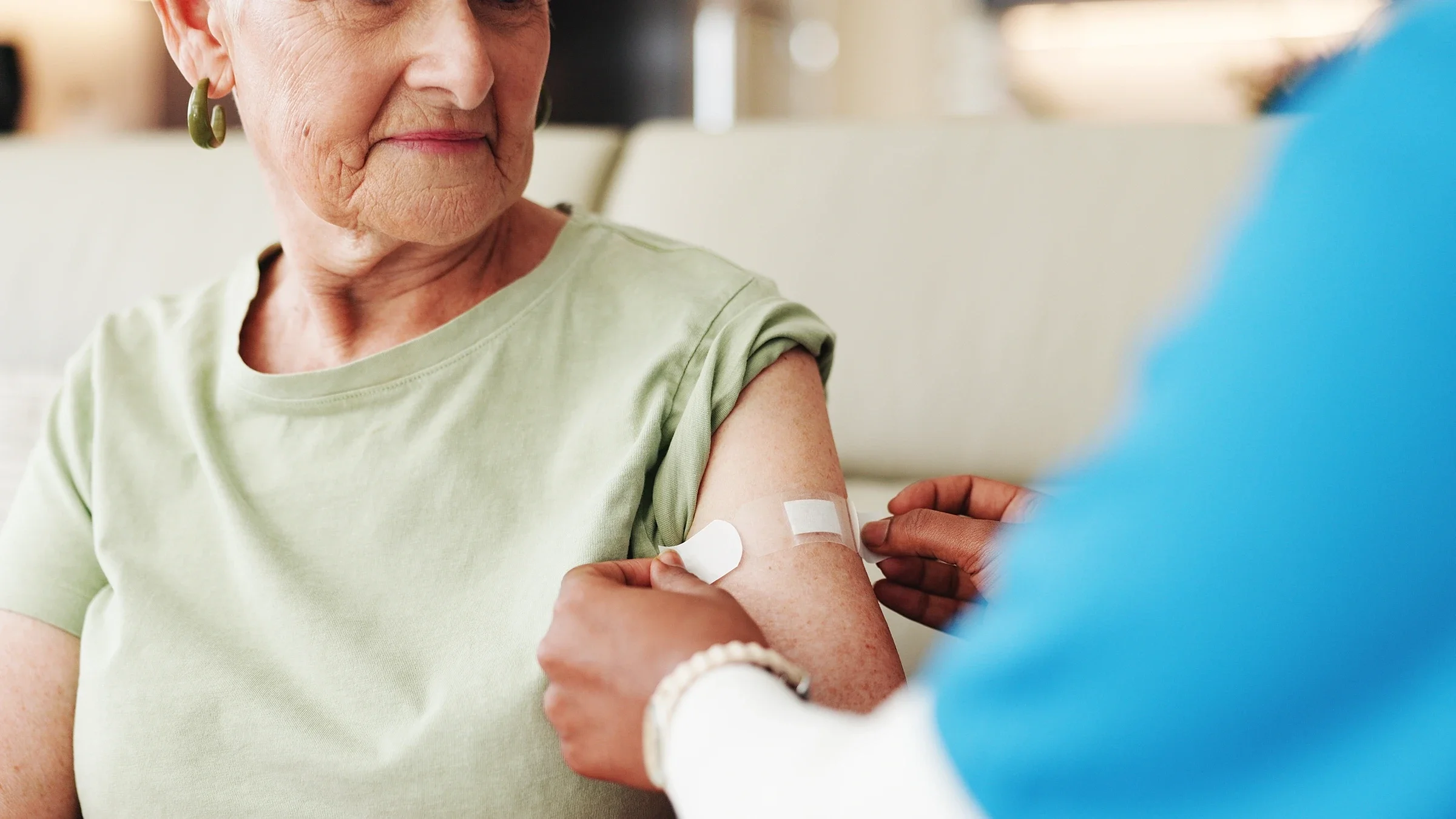 A woman receives a bandage on her arm after a vaccine shot.
