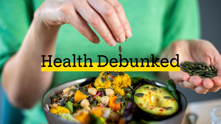 Close-up of a person sprinkling seeds onto their meal. There is added text on top reading “Health Debunked” with a yellow highlight bar behind it.